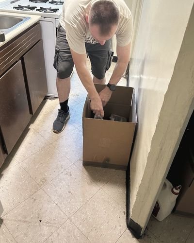A crew member packs a box on a kitchen floor